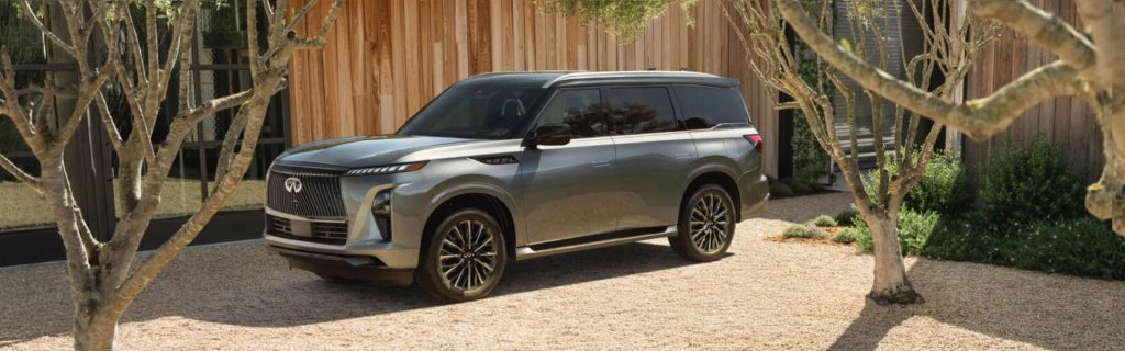 Silver Infiniti QX80 parked in a gravel courtyard.